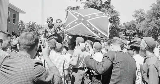 Rioting white students at University of Mississippi hoist a Confederate battle flag in a backlash against James Meredith’s attendance as the first Black student in 1962. (the confederate battle flag has long been a symbol of white insurrection)