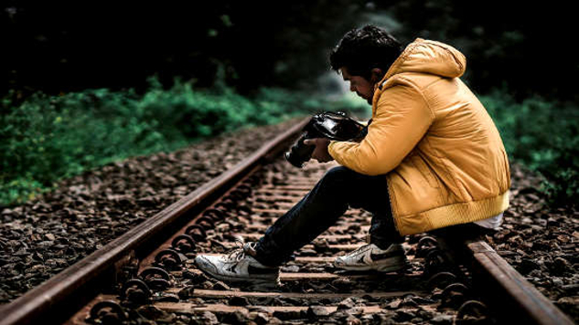 young man sitting on a railroad track 