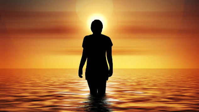 woman standing in the water at sunrise